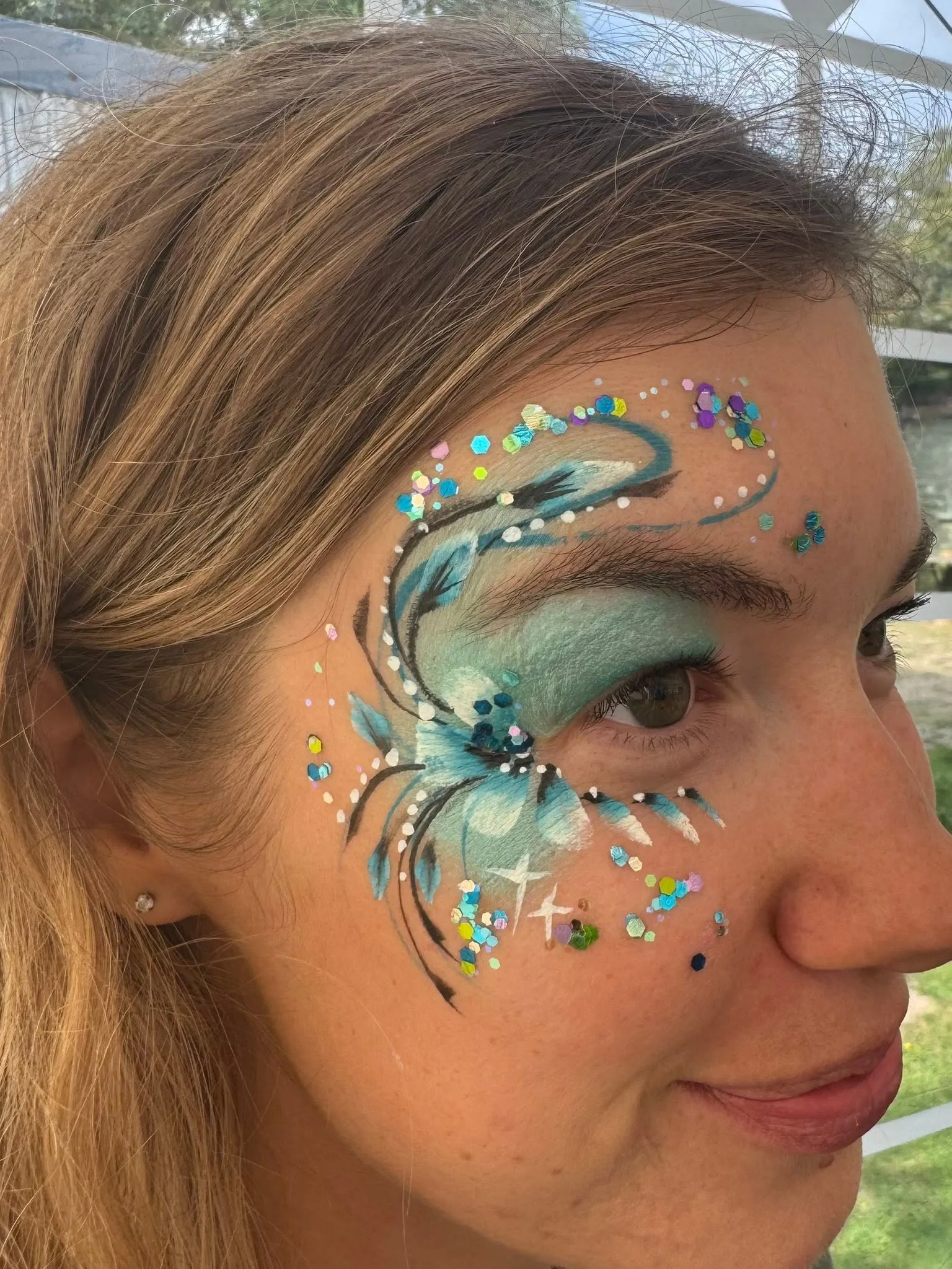 Woman with a teal glitter swirl eye design