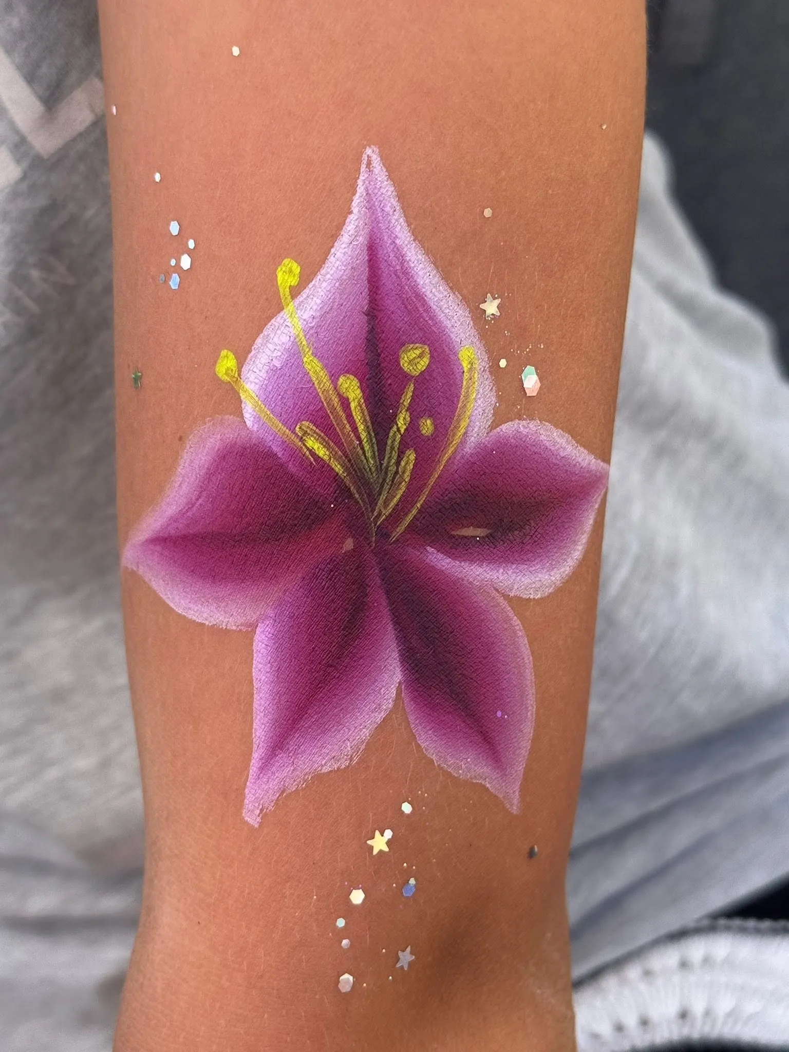 Painted purple lily on an arm