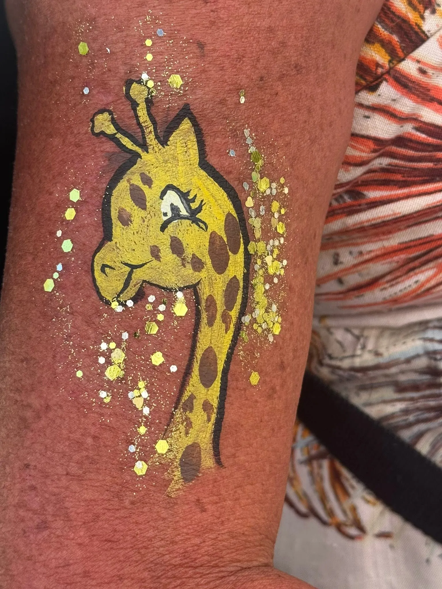 Painted giraffe with gold glitter on an arm