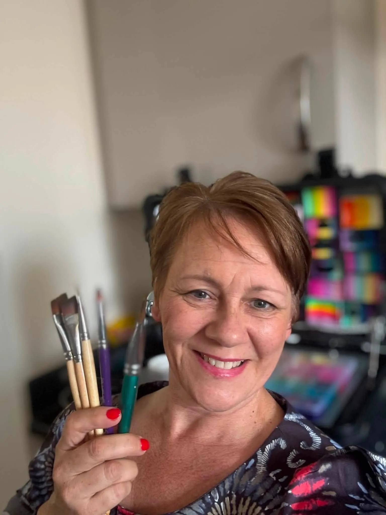 Kerry holding her paint brushes in front of her face painting kit